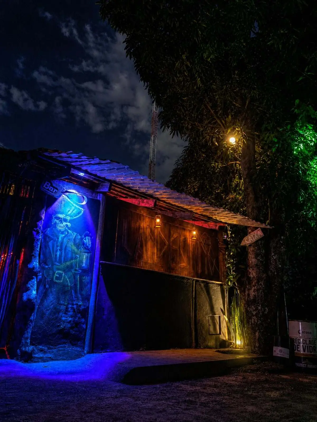 Salão do bar na vila, à noite, com mesas ocupadas
