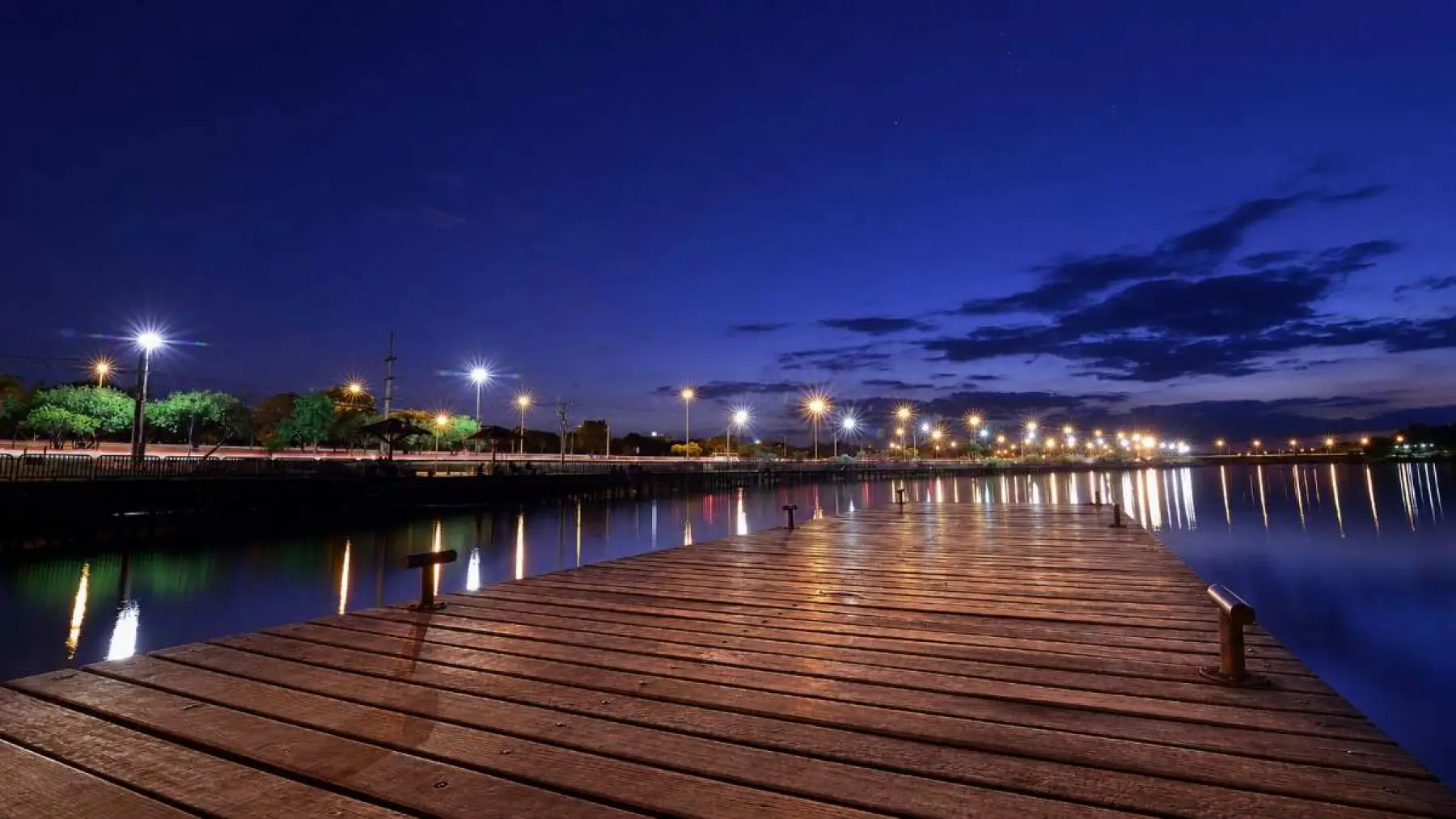 Deck do Cápsula Bar iluminado à noite, de frente para o Lago Paranoá