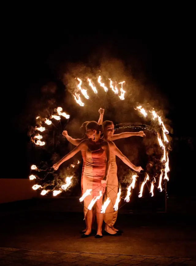 Artista girando aro de fogo diante do público, à noite