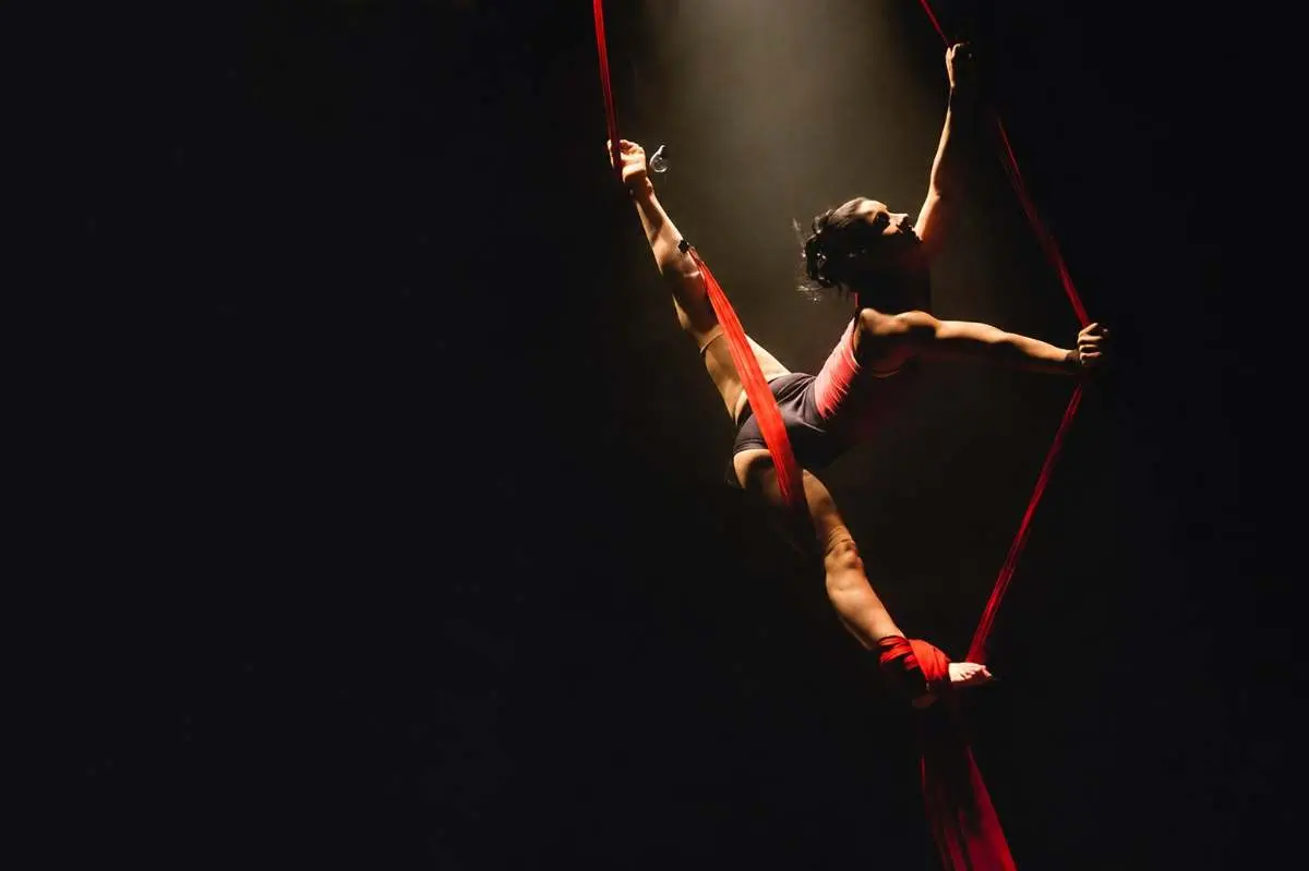 Acrobacia em tecido aéreo sob luz cênica